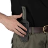 Mano afferra fodero Kydex per coltello tattico con manico mimetico verde, fissato a cintura.